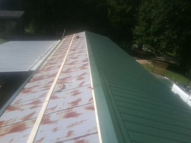 Old rusted panels beside newly installed green metal roofing — Wind Damage Roof Repair by Roofing Brothers in Soda Springs