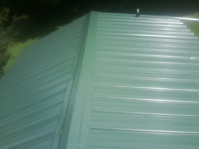 New green metal panels meeting at the ridge of a roof — Flat Roof Repair work by our crew in Soda Springs