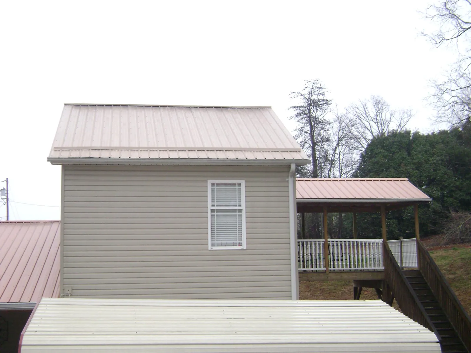 Tan metal roofs on a two story addition and attached porch, from a Roof Replacement job in Soda Springs