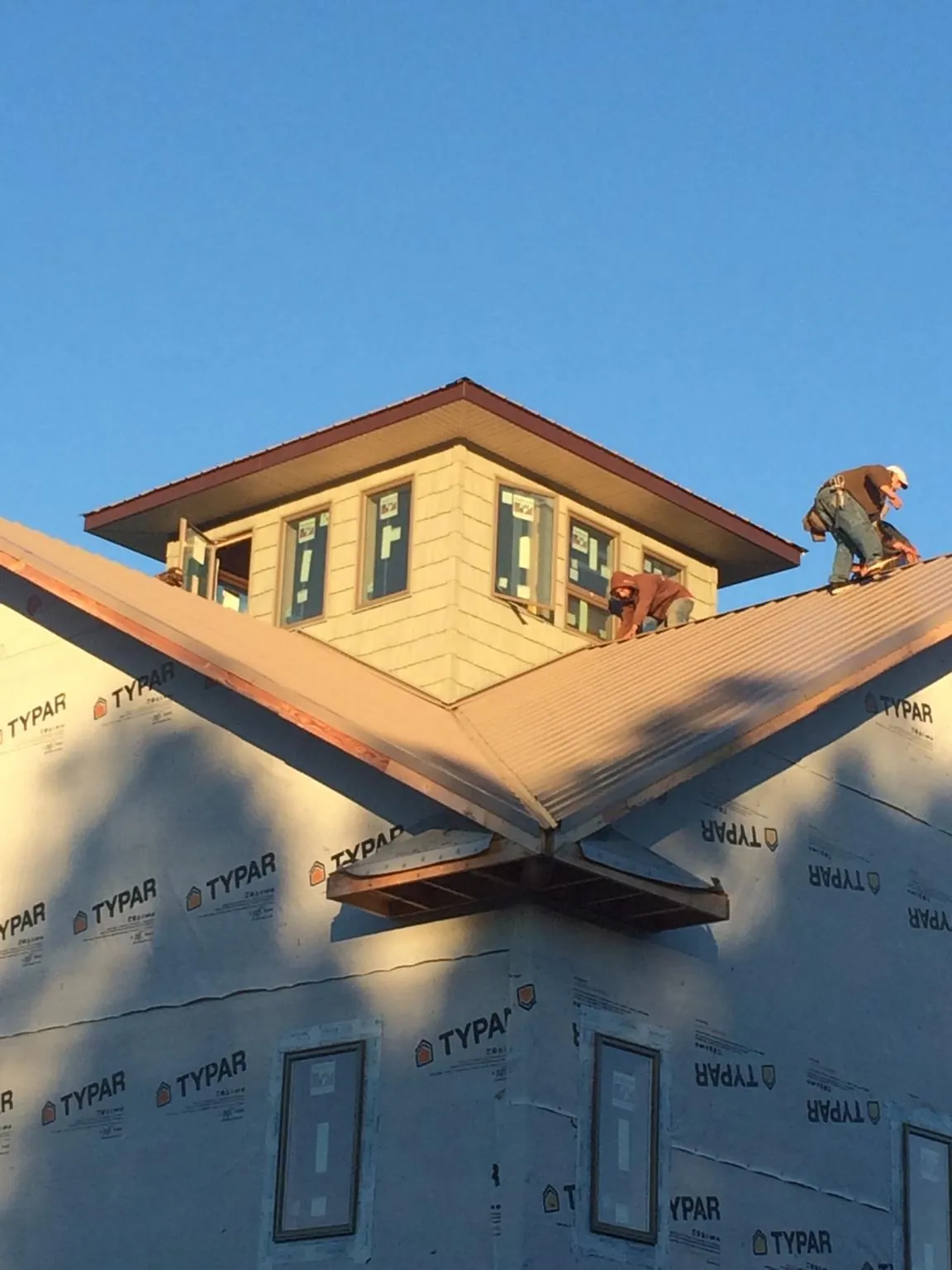 Roofers working around a rooftop cupola on a new metal roof at sunset — Roof Waterproofing in Soda Springs by Roofing Brothers